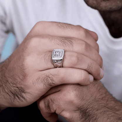 A close-up of a person wearing a silver championship ring featuring the number 23 and small diamonds, with a basketball design on the side. The person is clasping their hands.