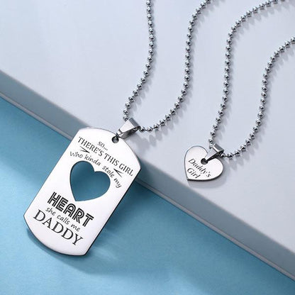 Silver necklace set: a dog tag engraved with "she calls me DADDY" and a heart pendant reading "Daddy's Girl" on a light blue box.