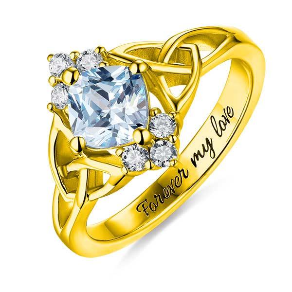 Gold Celtic knot engagement ring with blue center stone and 'Forever my love' engraving.