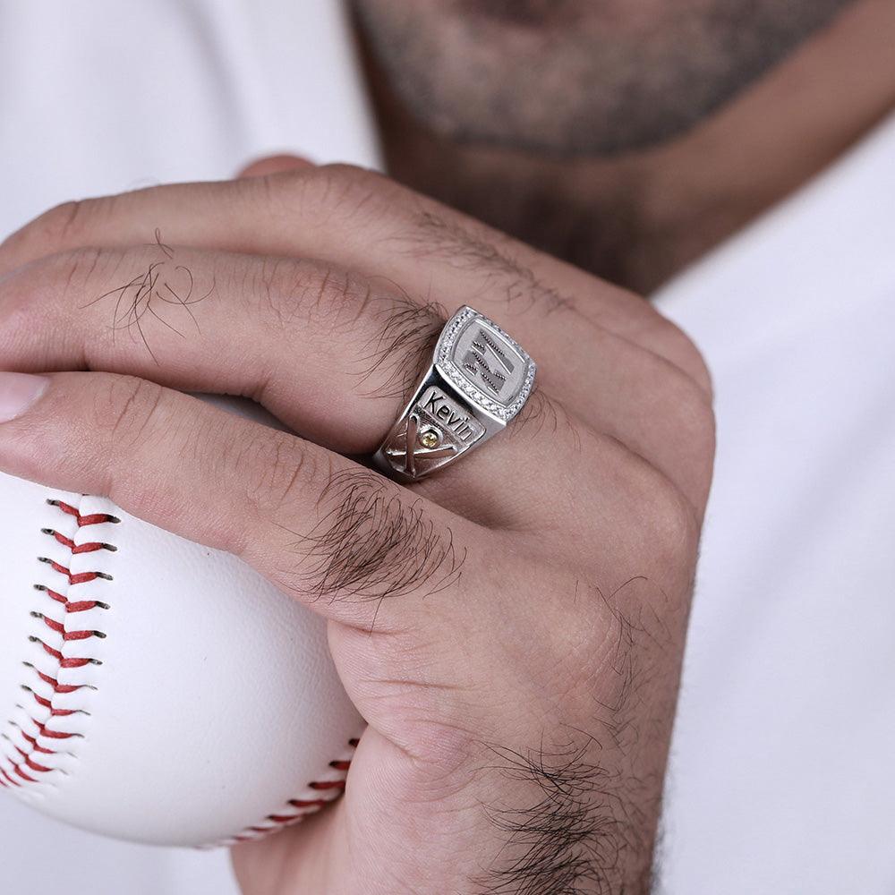 Man holding baseball showcasing custom 'Kevin' engraved signet ring with diamond-like details.