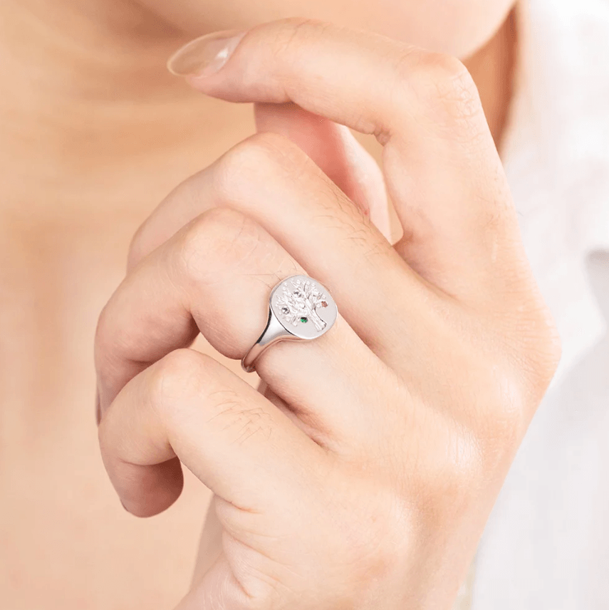 Hand wearing a silver family tree ring with colorful birthstones.