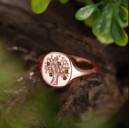 Rose gold family tree ring with embedded birthstones, on a natural wooden backdrop.