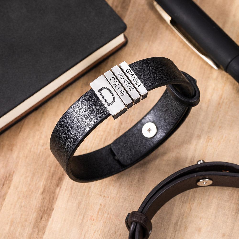 Black leather bracelet with silver beads engraved 'Gianna', 'Christine', 'Collin' on a wooden table with a book and pen