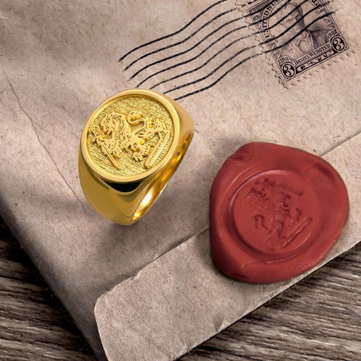 Gold signet ring with family crest on a vintage envelope with a red wax seal and postage stamp.