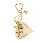 A gold nursing brooch shaped like a stethoscope, featuring a medical emblem and personalized text reading "Sophia" and "Grad 2022."