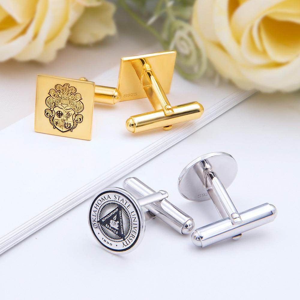 A pair of gold and silver cufflinks, one with a heraldic lion, the other with a university seal.