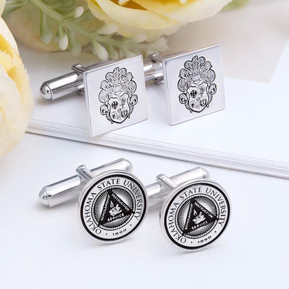 Silver square and round cufflinks with intricate designs, on white with a yellow flower nearby.