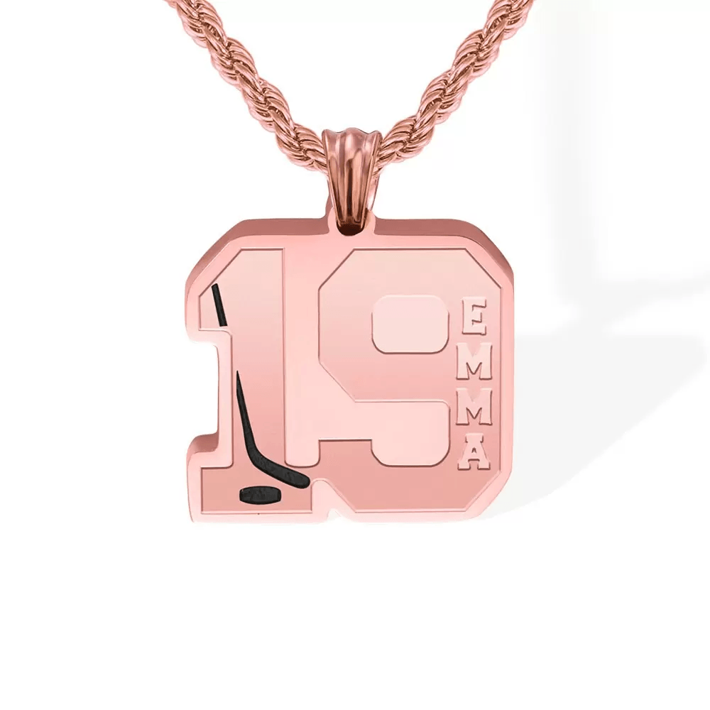 A rose gold hockey-themed necklace featuring the name "EMMA" and number 19 with a hockey stick design, displayed on a rose gold chain.