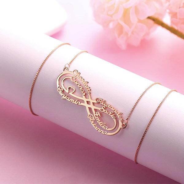 Rose gold infinity necklace with personalized names on a soft pink backdrop.