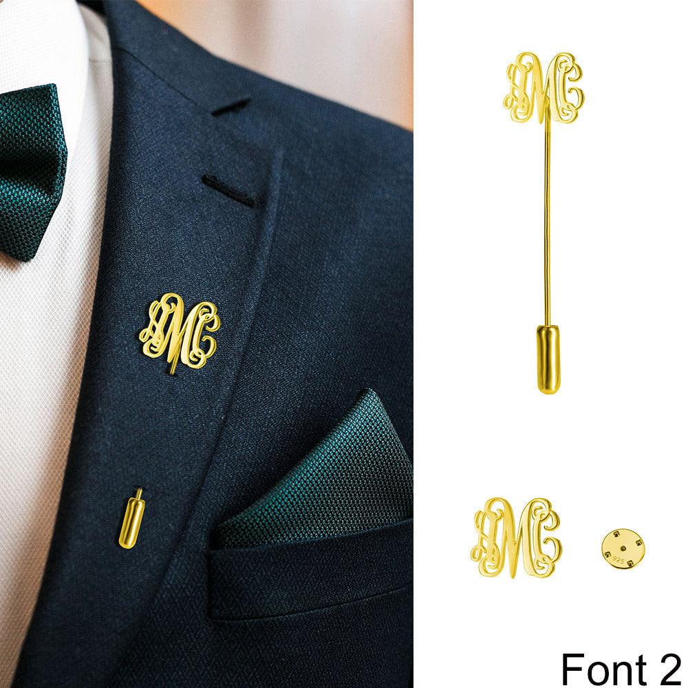 Suit with 'AMC' gold monogram lapel pin, white shirt, green tie, and matching pocket square.