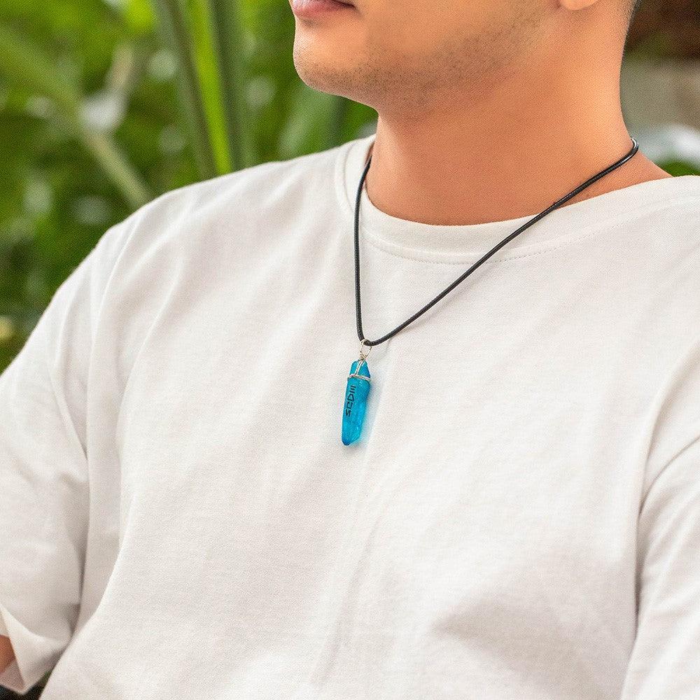 Man in white shirt with a blue kyber crystal necklace featuring Aurebesh inscription.