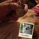 A hand holds a silver pendant engraved with a dog's portrait. Below, a photo of the same dog, named Scribbles, is shown for reference.