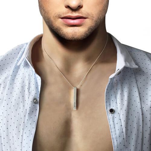 Man wearing a white polka dot shirt and a silver bar pendant necklace.