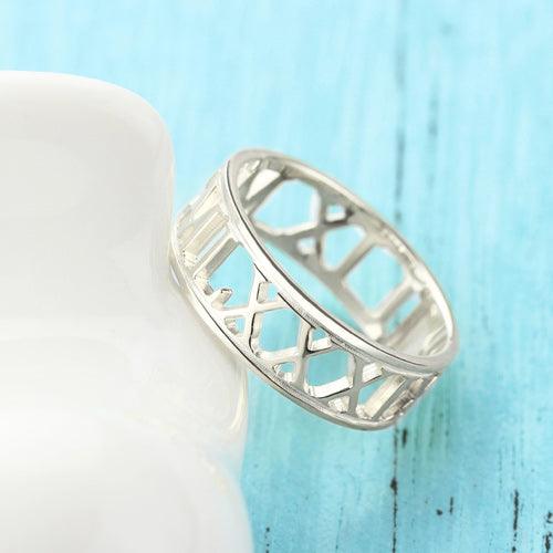 A silver sculpted cut-out style ring with the Roman numerals "MCMXIX" (1919) prominently displayed, placed on a light blue and white background.