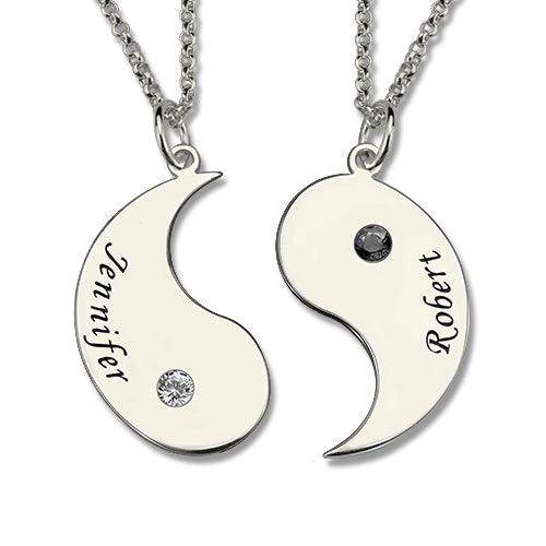 A yin-yang necklace set with two separate chains; each half has a name engraved ("Jennifer" on the left and "Robert" on the right) and a gemstone embedded.