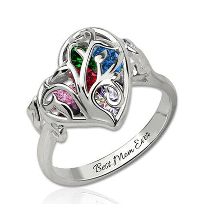 A silver heart-shaped ring with intricate designs features five colorful gemstones and an engraving that reads "Best Mom Ever."