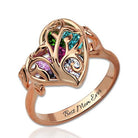 A rose gold heart-shaped ring with intricate designs features five colorful gemstones and an engraving that reads "Best Mom Ever."