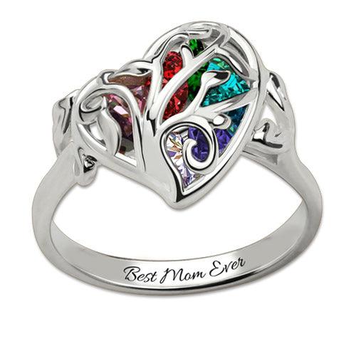 A silver heart-shaped ring with colorful gemstones and intricate designs, engraved with "Best Mom Ever" on the band.