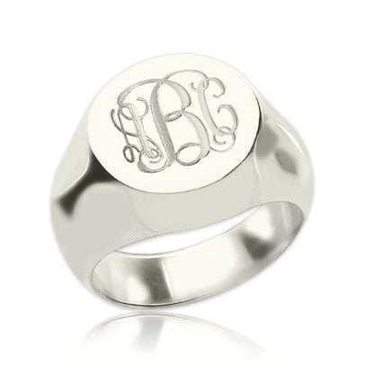 A polished silver signet ring with engraved ornate initials "LBC" on its flat top surface.