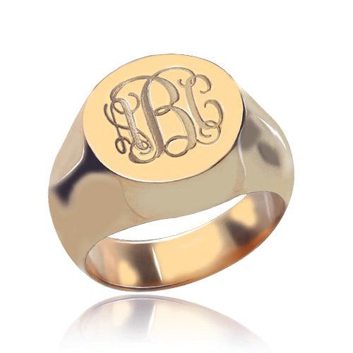 A polished rose gold signet ring with engraved ornate initials "LBC" on its flat top surface.