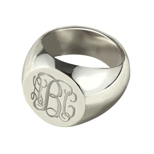 A polished platinum signet ring with engraved ornate initials "LBC" on its flat top surface.