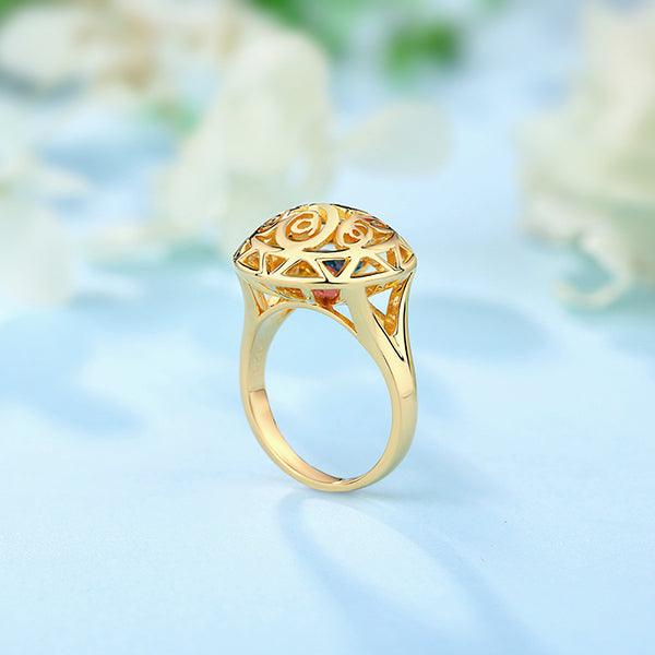 Gold ring with an intricate filigree design and triangular blue gemstones set in a circular pattern.