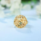 Gold filigree ring with a central eye-shaped gemstone surrounded by intricate scrollwork.