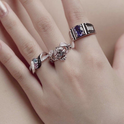 Hand wearing multiple silver rings, including a Claddagh ring with "Love you forever" engraving and a gemstone heart