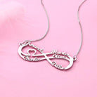 Silver double infinity necklace featuring the names Amanda, Charles, Hunter, Olivia, and Dillon in a delicate script, with a small heart, displayed on a pink background.