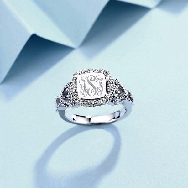 Elegant silver ring with monogram initials 'ASJ', adorned with a diamond halo and intricate side designs.