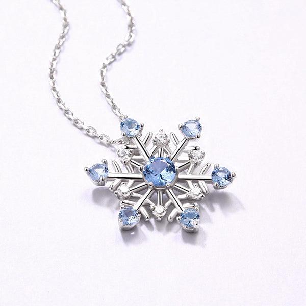 Elegant snowflake pendant necklace in pure silver with sparkling blue stones, perfect for Christmas and winter gifts, displayed on a delicate chain.