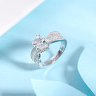 Elegant sterling silver engagement ring with a sparkling princess cut gemstone, shimmering accent stones, and personalized engraving, displayed on a light blue background.