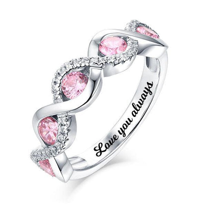 A silver ring with pink gemstones in a twisted design, surrounded by small clear stones. The inside of the band is engraved with the words "Love you always".