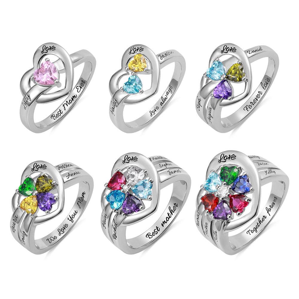 Collection of personalized heart-shaped rings with different birthstones and engraved names, symbolizing love and family, on a white background.