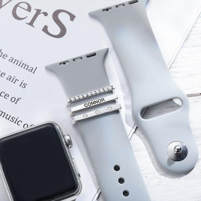 Gray Apple Watch band with personalized silver and diamond-like engraved charms featuring the name "Connor.