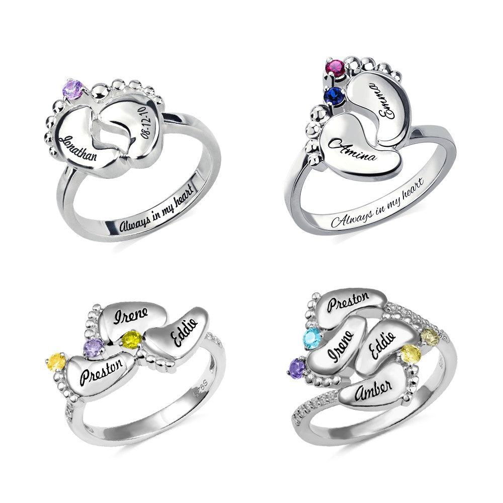 A collection of four silver rings with engraved baby feet designs, personalized with names and birthstones, featuring the inscription "Always in my heart."