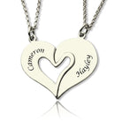 A silver heart-shaped pendant split into two halves, with "Cameron" engraved on the left half and "Hayley" engraved on the right half, each attached to a chain.