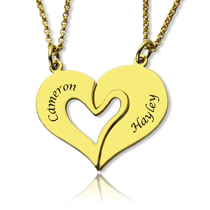 A gold heart-shaped pendant split into two halves, with "Cameron" engraved on the left half and "Hayley" engraved on the right half, each attached to a chain.