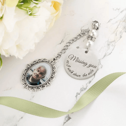 Memorial photo charm with 'Missing you' inscription and white bouquet on marble.
