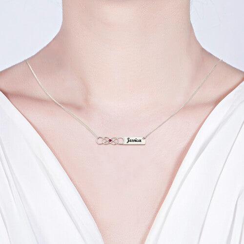 Model wearing Personalized Double Infinity Knot Necklace with Birthstone in Sterling Silver, featuring the name "Jessica" engraved on a rectangular pendant.