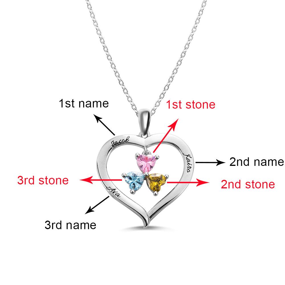 A heart-shaped silver necklace with three heart-shaped birthstones, marked to indicate the first, second, and third stones and engraved names "Jacob," "Katira," and "Ayla."