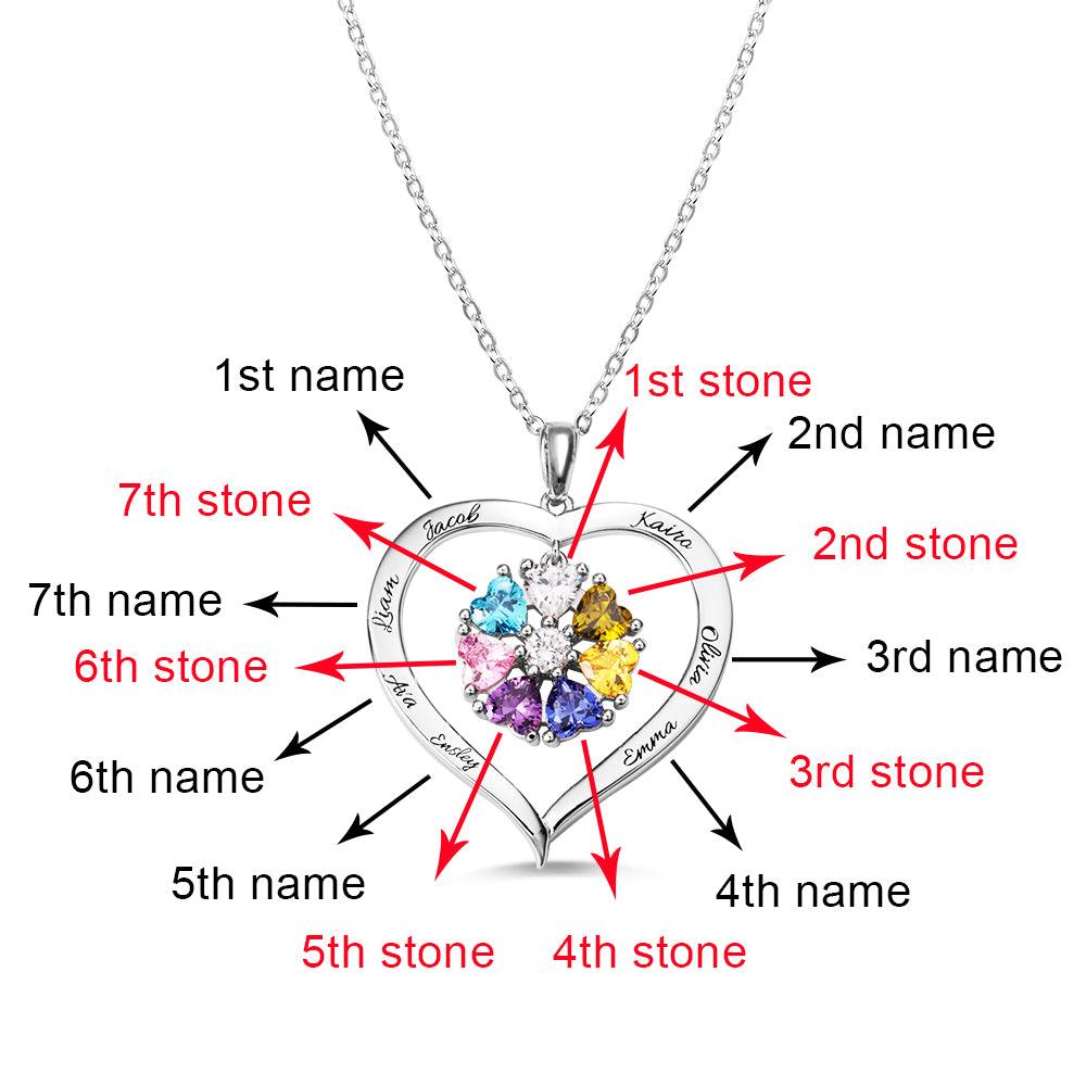 A heart-shaped silver necklace with seven heart-shaped birthstones, marked to indicate the first through seventh stones and engraved names "Jacob," "Katira," "Olivia," "Emma," "Ava," "Liam," and "Easley."