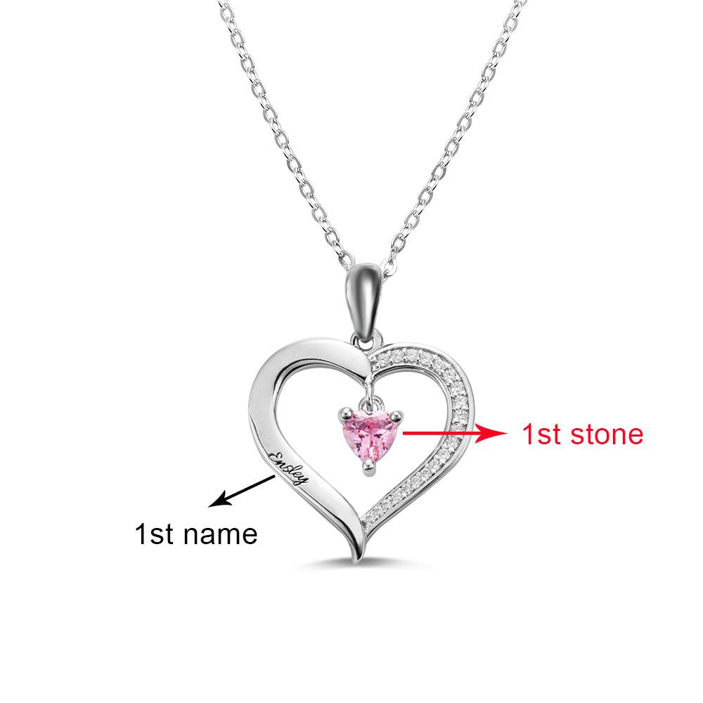 A heart-shaped silver necklace with a single pink heart-shaped birthstone and the engraved name "Ashley," marked to indicate the first name and first stone.