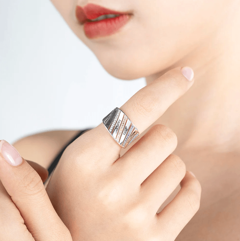 Woman showcasing a silver personalized ring with engraved names and birthstones, highlighting its elegant and custom design on her finger.