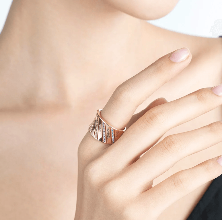 Woman wearing a rose gold personalized ring with engraved names and birthstones, showcasing its elegant and custom design on her finger.