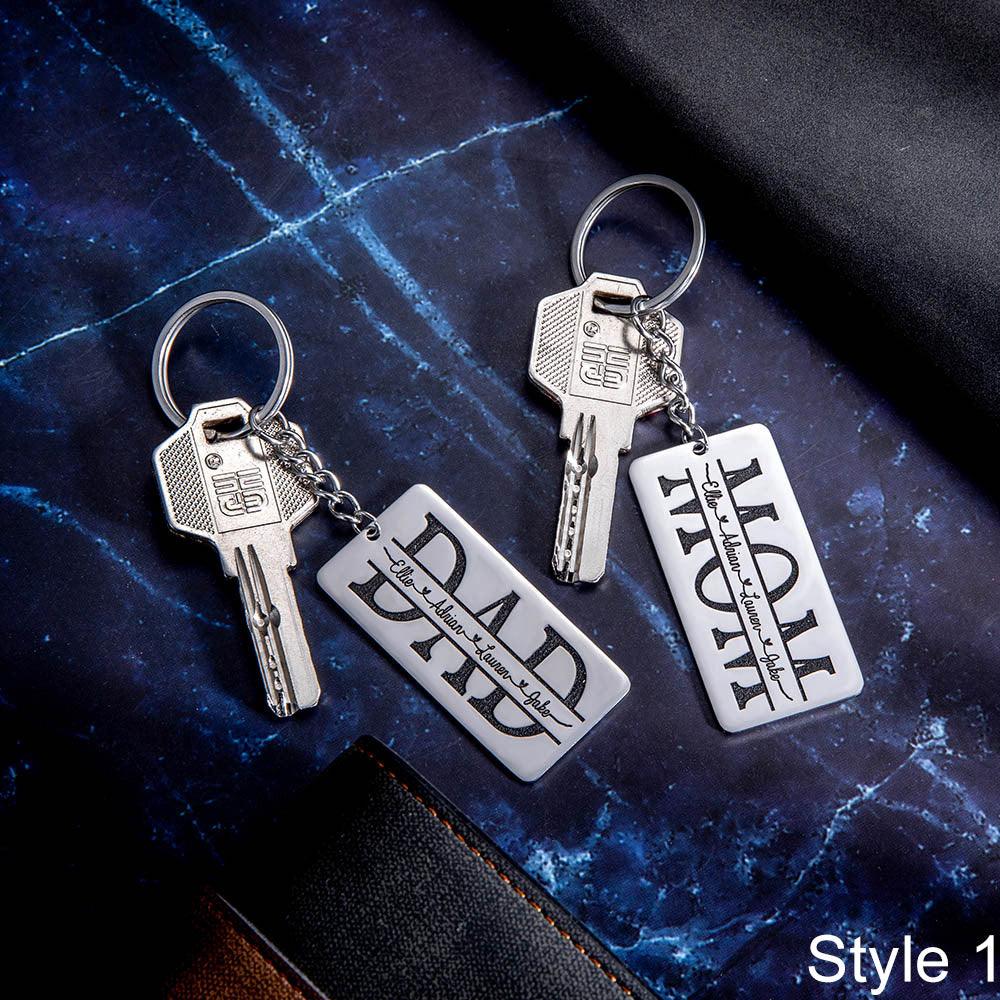 Two keychains labeled "DAD" and "MOM" with keys attached, on a dark marble surface.