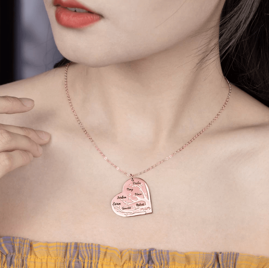 Woman wearing a rose gold heart-shaped pendant necklace with a family tree design, featuring names Dalia, Tony, Vince, Jordan, Evan, Genesis, Robert, and "mom" at the bottom.