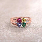 Rose gold ring with four heart-shaped gems in various colors, engraved with names "Olivia," "Rebecca," "Sandy," "Joshua."