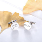 Silver cufflinks with 'Love you forever!' and '❤ Amelia' on a white surface with a golden leaf.