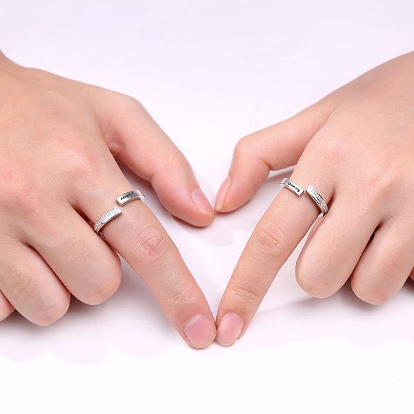 Couple wearing personalized sterling silver rings with engraved names, showcasing their connection by forming a heart shape with their fingers. Symbol of eternal love.